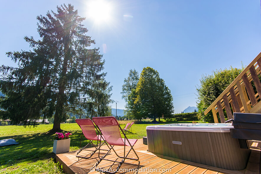Chalet Toubkal Samoëns - Terrasse ensoleillée avec bain à remous et jardin au-delà