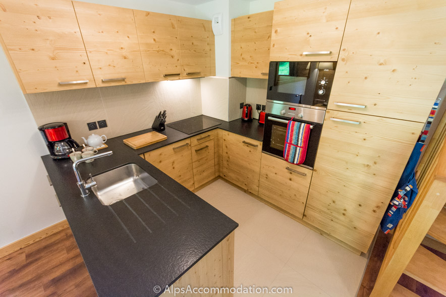 Appartement CH8 Morillon - La cuisine moderne en bois est entièrement équipée avec tout ce dont vous pourriez avoir besoin ainsi que des plans de travail en pierre